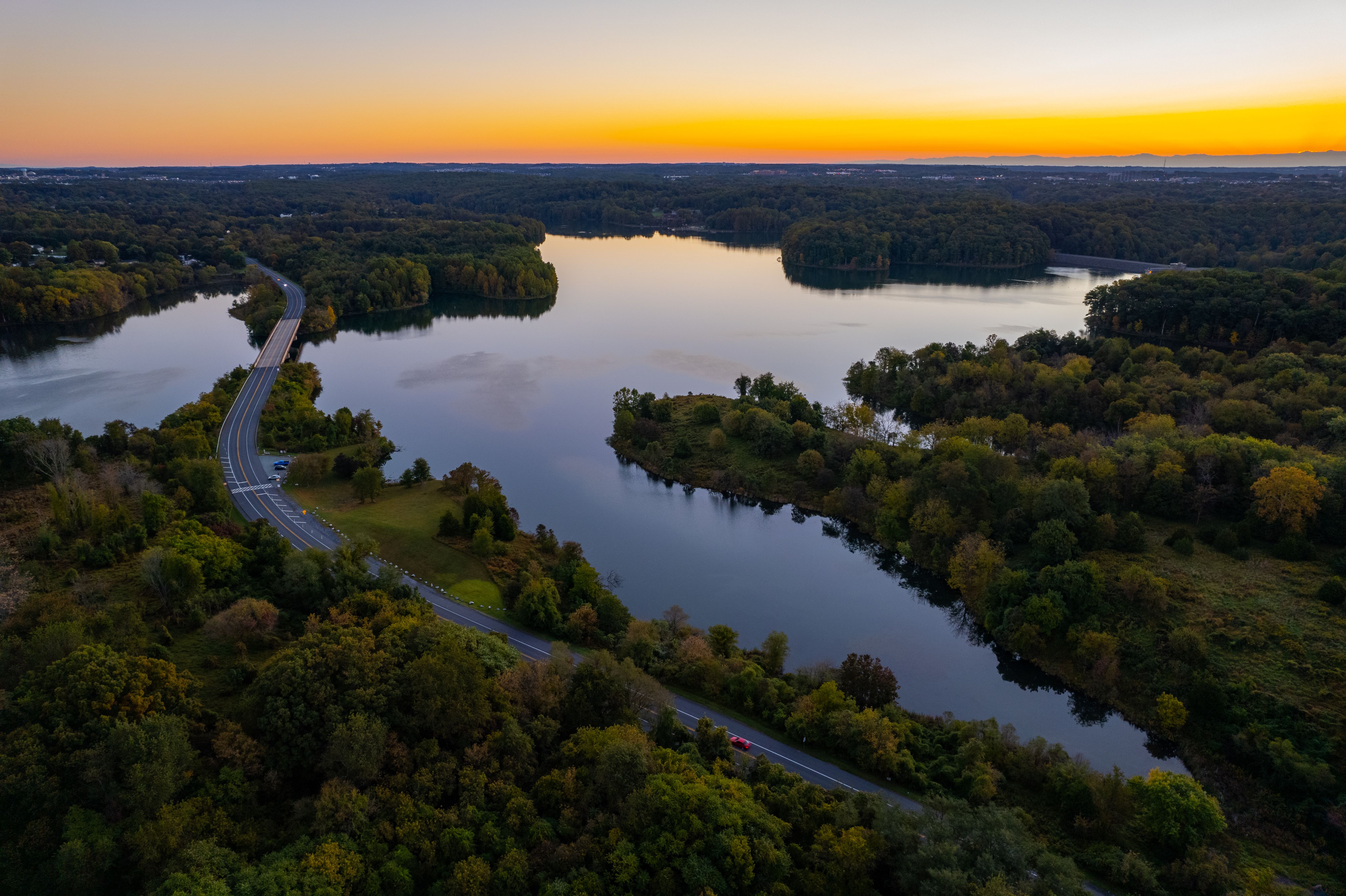 Aerial view of a highway road next to a lake at sunrise